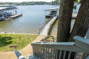 A lakeside dock with a wooden deck, a covered area, and a view of the water.
