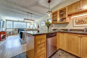 A modern kitchen with wooden cabinets, a dishwasher, and a dining area with a table and chairs.
