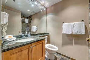 Ein Badezimmer mit Waschbecken, Spiegel, Handtuchhalter und Toilette.