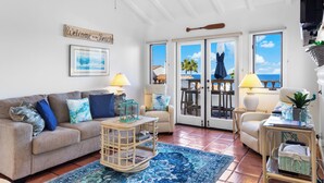 A living room with a sofa, armchairs, a coffee table, and a view of the beach through large sliding doors. - H962: Great Ocean Views, Golf Cart + Only 10 Steps + King Bed + Fireplace (Avalon)