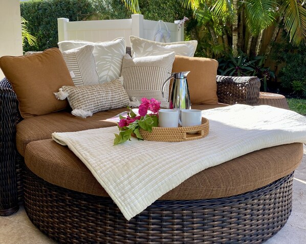 A wicker sofa with cushions, a tray with cups and flowers, and a white throw blanket. - Luxe East Boca Retreat – Private Home w/ Resort Pool, Perfect Location! (Boca Raton)
