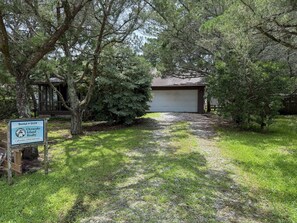 A residential property with a garage, surrounded by trees and a grassy yard.