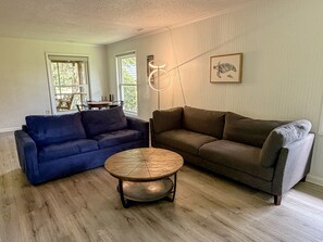 A living room with two sofas, a coffee table, and a wall-mounted lamp.