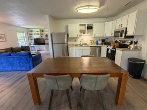 A modern kitchen with white cabinets, a wooden dining table, and two chairs.