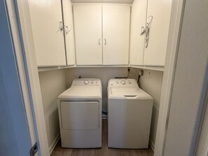 A compact laundry room with two washing machines and cabinets above.