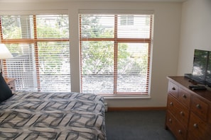 Un dormitorio con una cama, un aparador y un televisor sobre un mueble de madera.