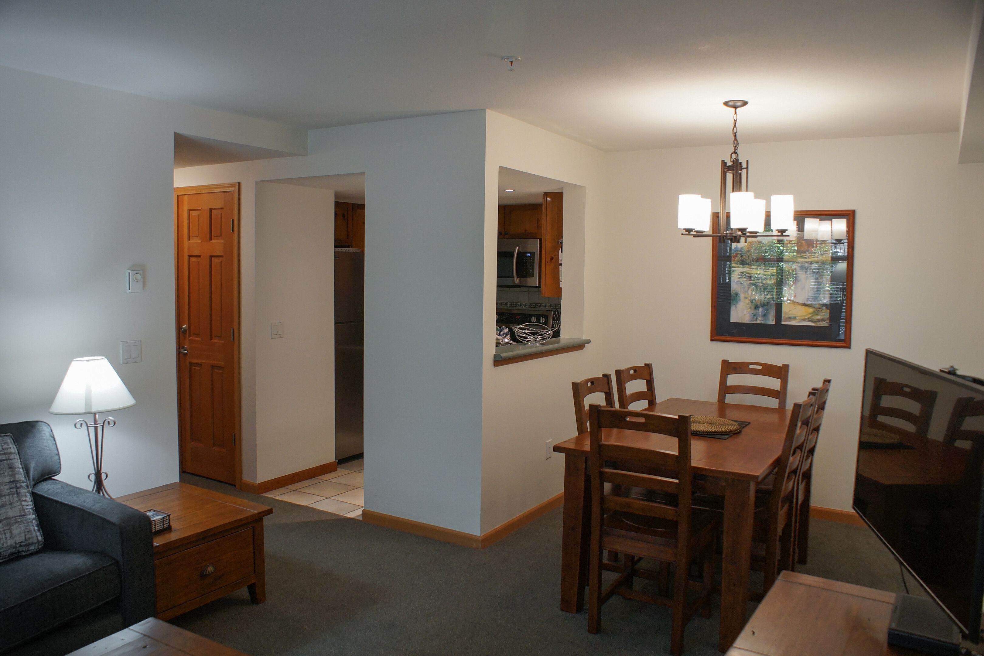 A compact living space with a dining area, kitchenette, and a television.