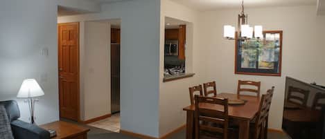 A compact living space with a dining area, kitchenette, and a television.