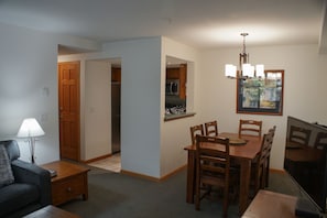 Un espacio habitable compacto con comedor, kitchenette y televisor.
