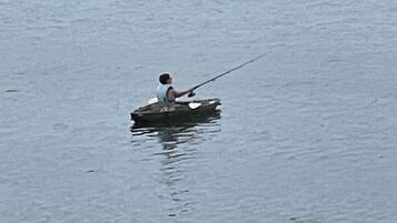 A person fishing from a small boat on calm water.