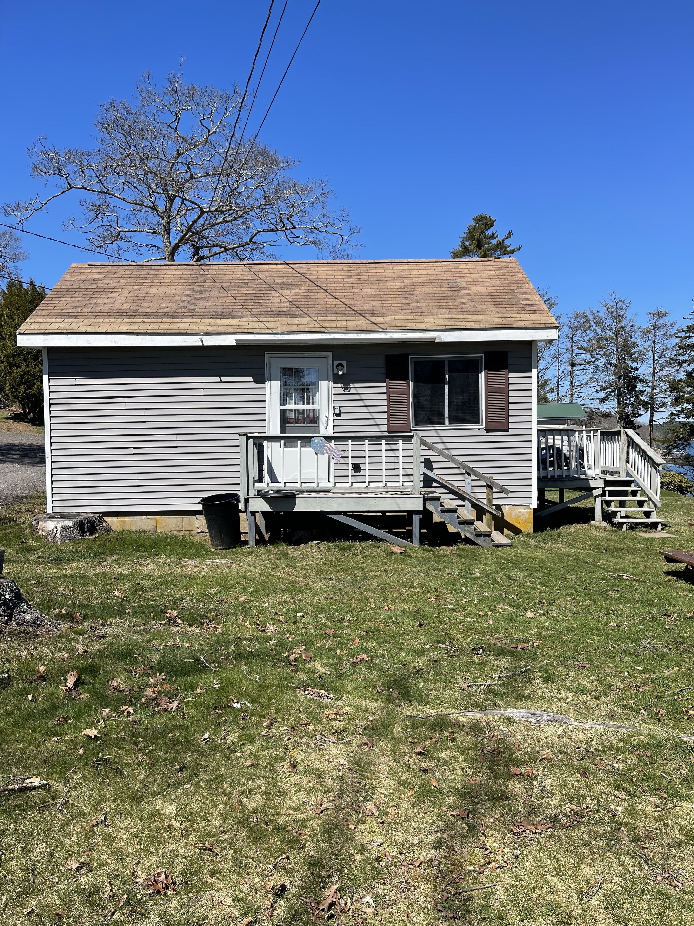 A single-story house with a front porch, a small deck, and a staircase leading to the front door.