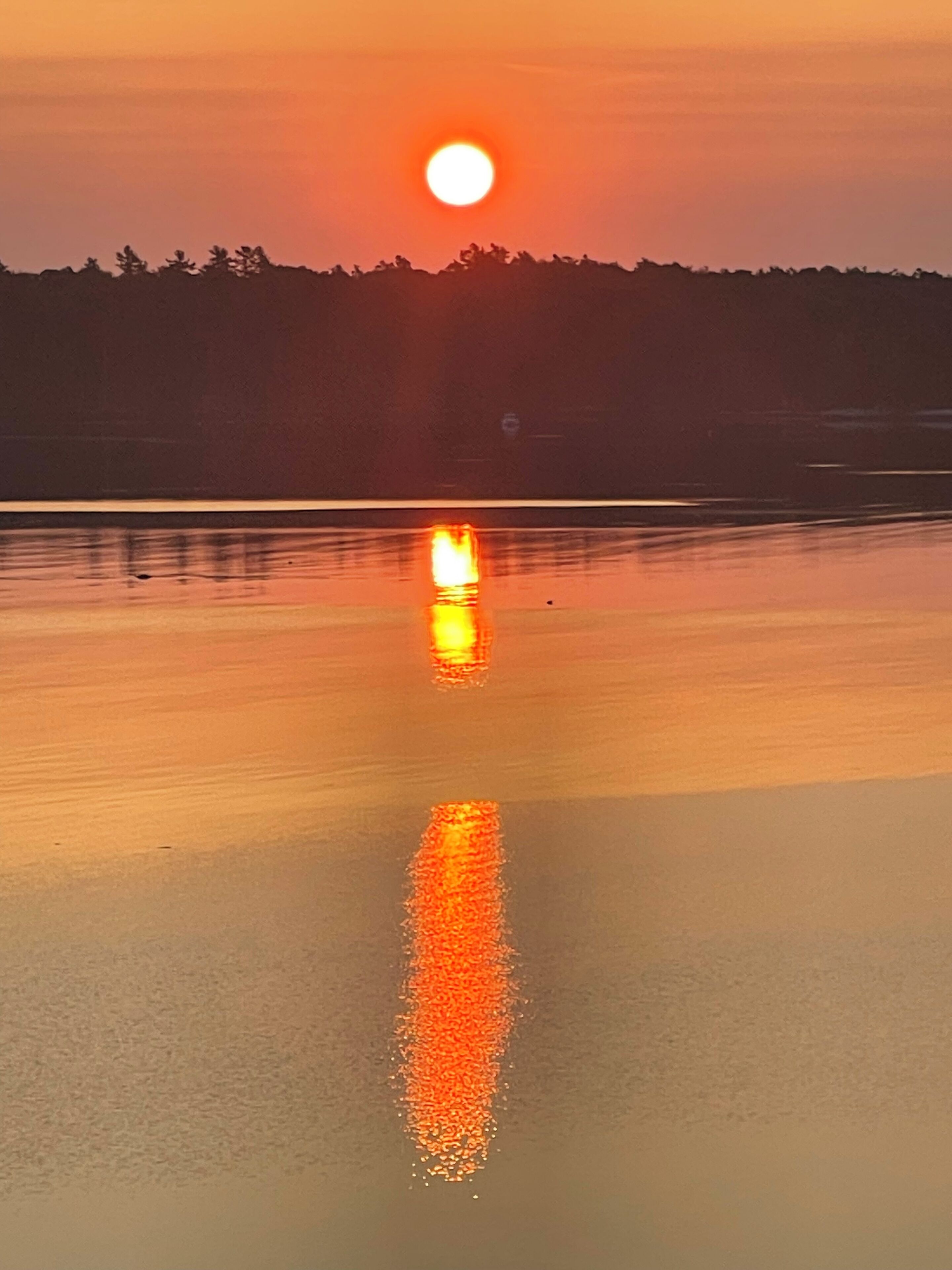 Un capvespre sobre un conjunt d'aigua tranquil·la amb el reflex del sol.