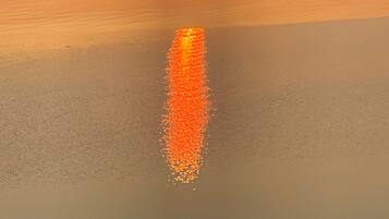 A sunset over a calm body of water with a reflection of the sun.