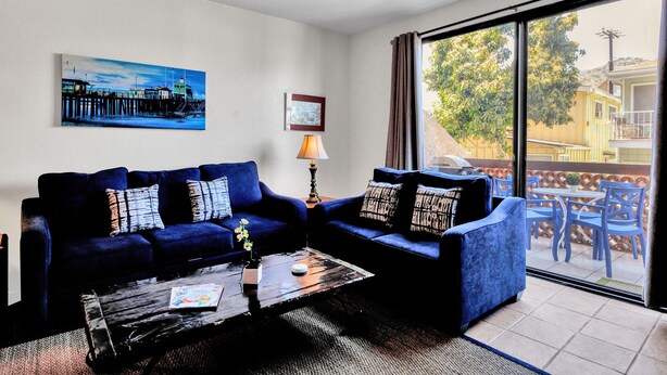 Ein Wohnzimmer mit zwei blauen Sofas, einem Couchtisch, einer Lampe und einem Gemälde an der Wand.