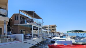 A marina with boats docked, a building with a balcony, and a clear blue sky.