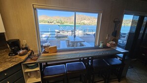 A kitchen with a large window overlooking a dock and water, a coffee maker, and a jar of pretzels.