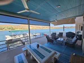 Una terraza techada al aire libre con mesa de billar, sillas y vistas a un lago y montañas.