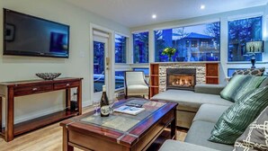 A living room with a fireplace, a television, a sofa, and a coffee table. - Greystone Lodge 109 Ski-in/Out by Acer Vacations (Whistler)