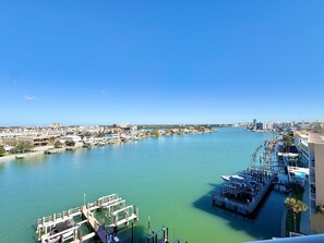 A marina with docks and boats, a clear blue sky, and a cityscape in the background.