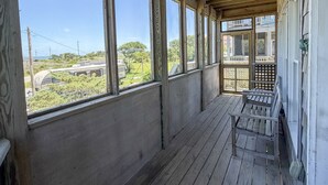 A covered porch with large windows, wooden beams, and a bench. - Ms Joy Bell:  Pet friendly, decks, screened porches, distant waterview (Ocracoke)