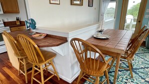 A kitchen with wooden chairs, a dining table, and a patterned rug. - Ms Joy Bell:  Pet friendly, decks, screened porches, distant waterview (Ocracoke)