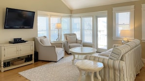A living room with a television, two armchairs, a sofa, a coffee table, and a lamp.
