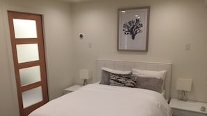 A bedroom with a bed, nightstands, a wall-mounted light, and a door with frosted glass panels.