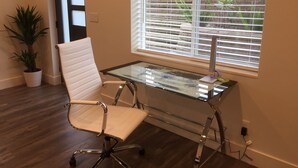 A modern office space with a glass desk, white office chair, and a 'NO SMOKING' sign on the wall.