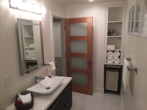 A bathroom with a white sink, a mirror, a towel rack, and a door with frosted glass panels.