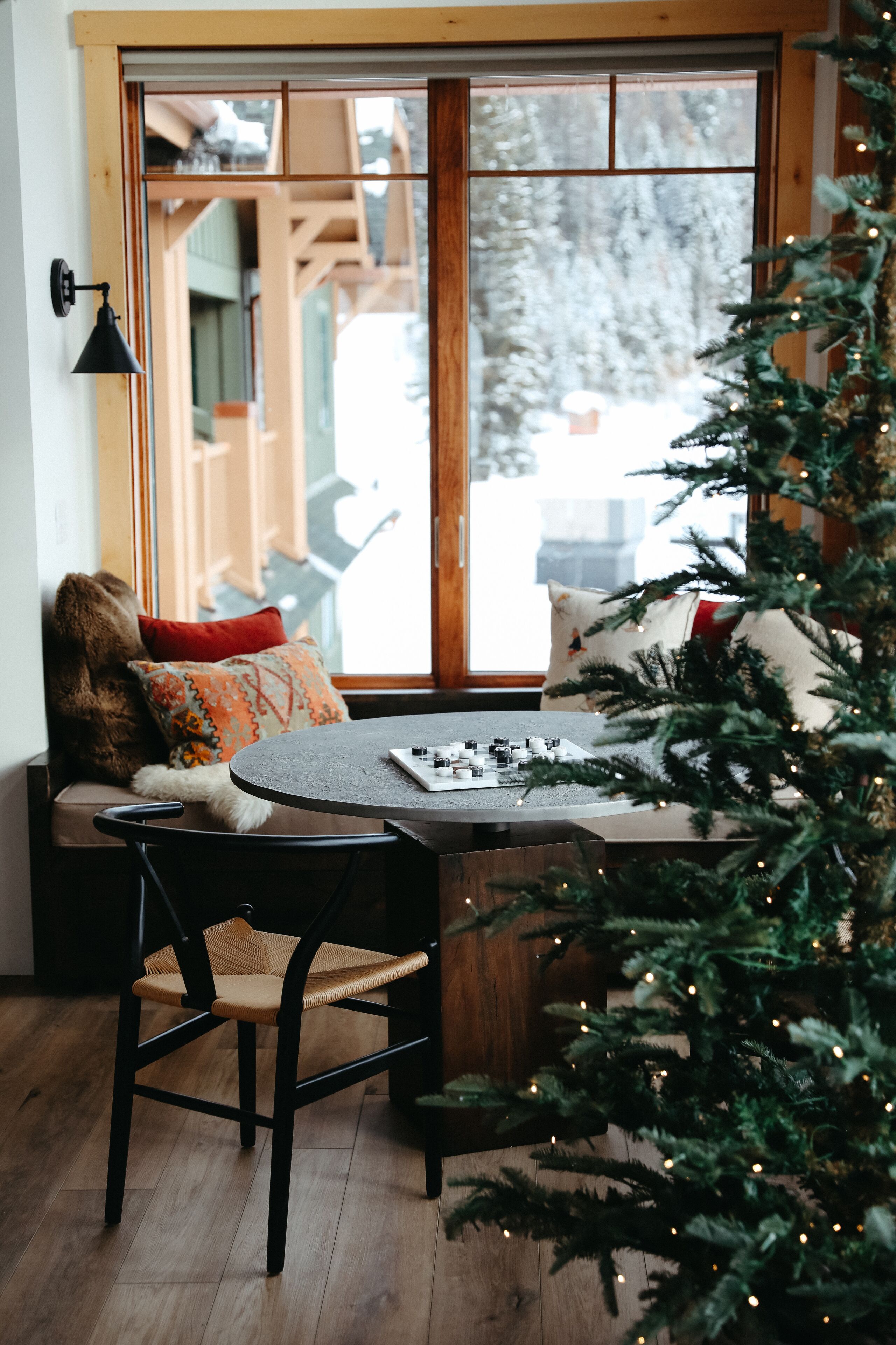 Un coin salon accueillant avec un banc en bois, une petite table et un sapin de Noël.