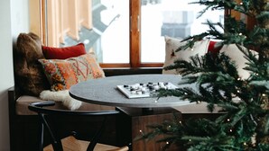 A cozy seating area with a wooden bench, a small table, and a Christmas tree. - Beautiful Ski-In/Ski-Out Penthouse (Whitefish)