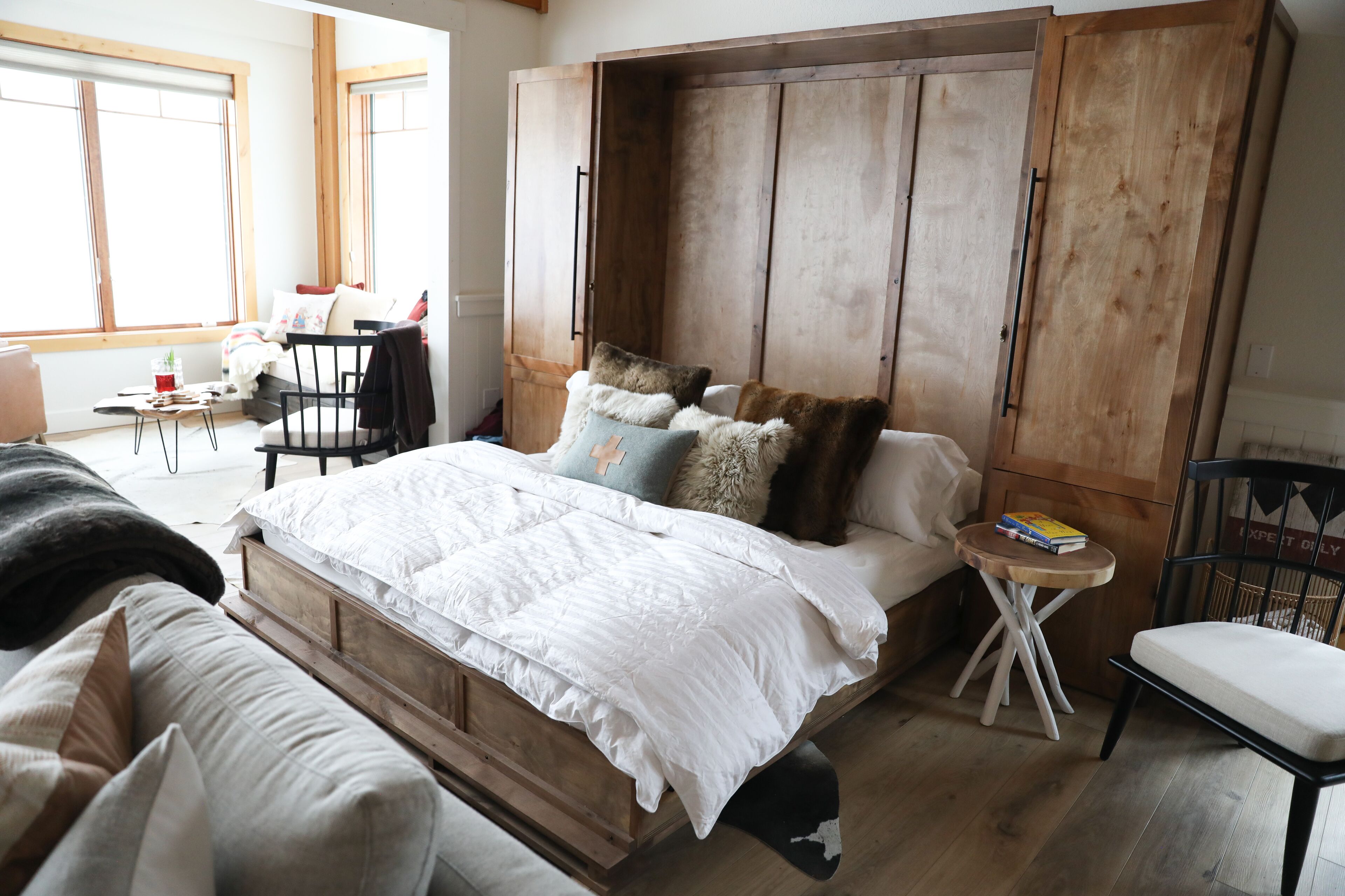 A bedroom with a wooden bed, a small round table, a chair, and a wardrobe.