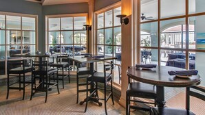 Un restaurant doté de grandes fenêtres, de tables et de chaises disposées pour accueillir les clients.