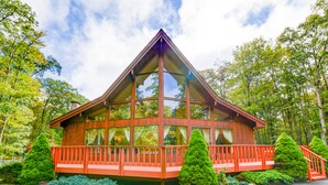 A wooden cabin with a triangular roof, large windows, and a red railing.