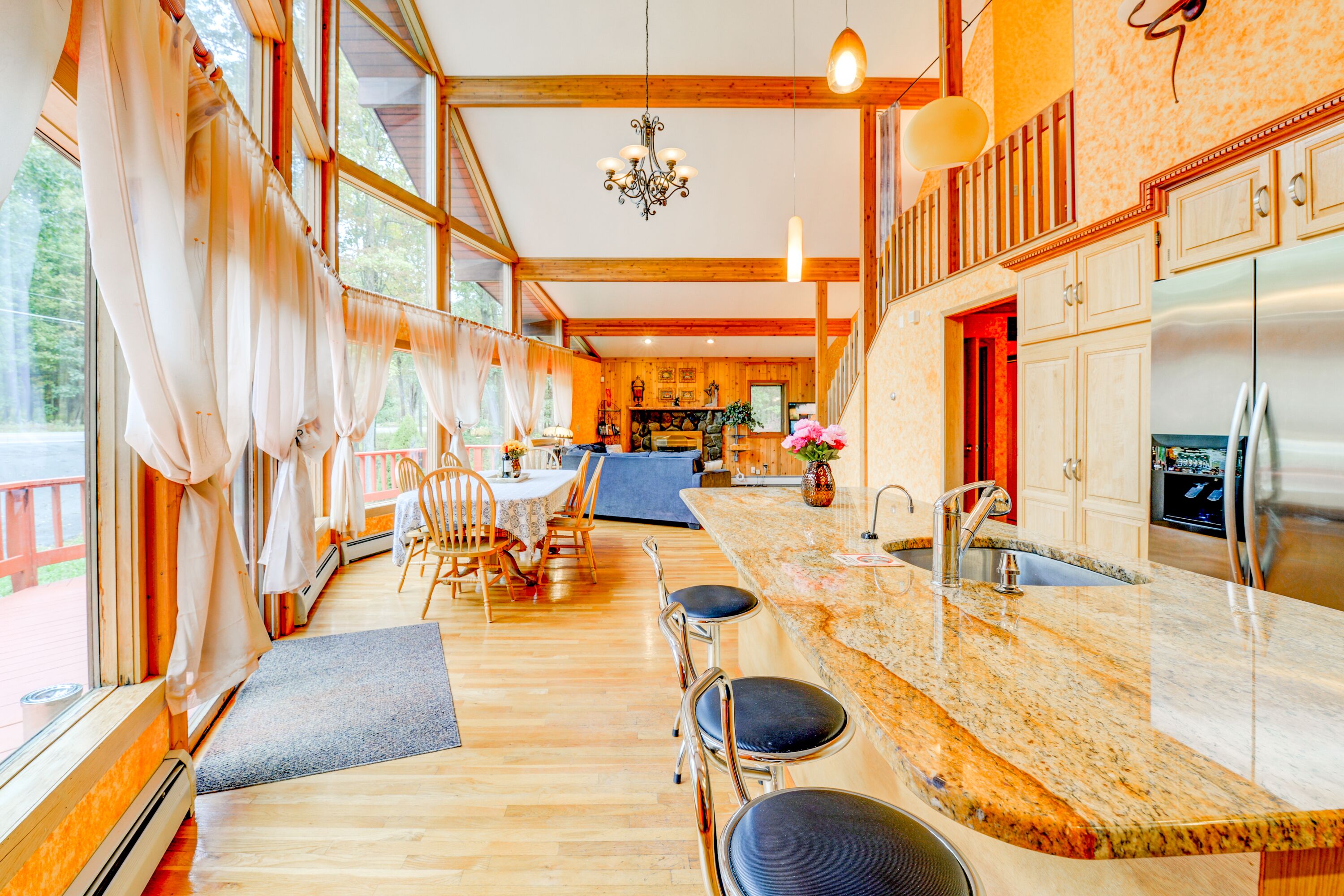 A spacious kitchen with a large island, wooden beams, and a view of the outdoors.