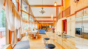 A spacious kitchen with a large island, wooden beams, and a view of the outdoors.