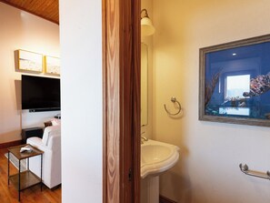 A bathroom with a white sink, a mirror, and a framed picture of a fish tank. - Down Creek Condo 102: Luxurious, reverse floor plan, in the Village. (Ocracoke)