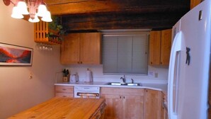 Une cuisine de taille réduite, avec des meubles de rangement en bois, un réfrigérateur blanc et une table à manger en bois.