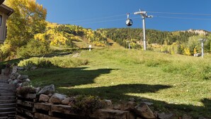 A mountain landscape with a wooden cabin, a stone wall, and a cable car system.