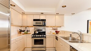 A modern kitchen with stainless steel appliances, beige cabinetry, and a double sink.