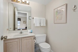 A bathroom with a sink, mirror, toilet, and towels.