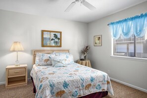 A bedroom with a bed, nightstand, lamp, and a window with curtains.