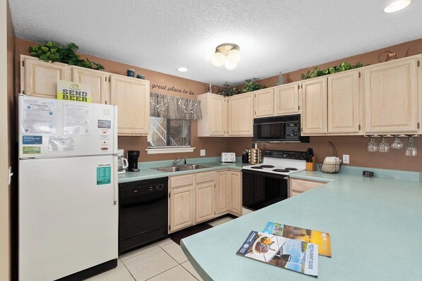 A kitchen with wooden cabinets, a microwave, a stove, a sink, and a dishwasher.