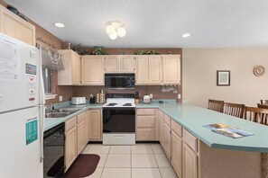 A kitchen with wooden cabinets, a microwave, a stove, and a dining area with chairs.