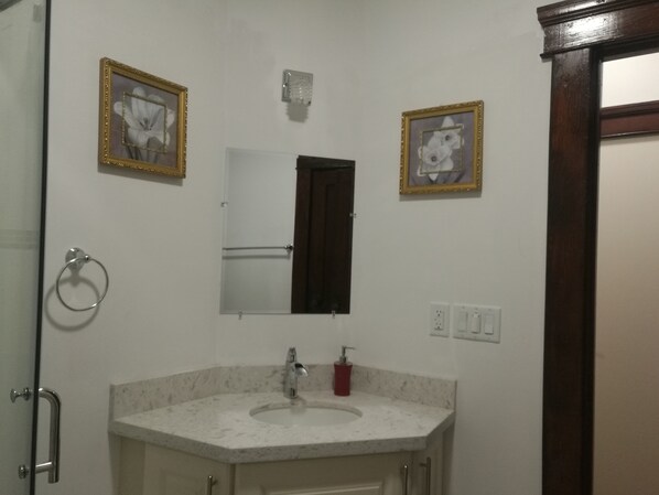 A bathroom with a sink, mirror, and two framed pictures on the wall.