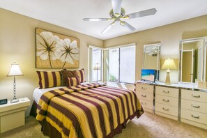 Une chambre d’hôtel avec un lit, un ventilateur de plafond, une grande fenêtre, un téléviseur et un miroir dans la salle de bain.
