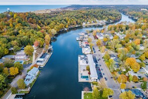 An aerial view of a marina with docked boats, surrounded by autumn-colored trees and a river. - TOP NOTCH NESTING @ ♥️ of DOWNTOWN w SEASONAL WATERFRONT POOL & HOT TUB ACCESS❣️ (Saugatuck)