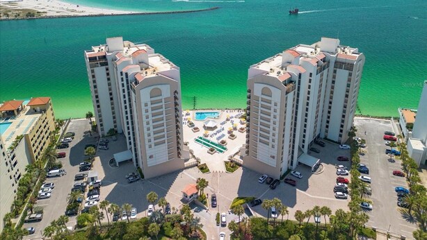 A high-rise hotel with a central pool and a view of the ocean.
