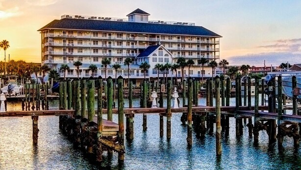A waterfront hotel with multiple balconies, a dock, and a pier with wooden posts.