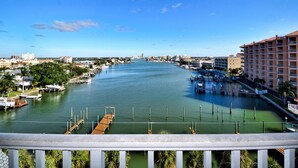 A marina with docked boats, a clear blue sky, and a cityscape in the background.